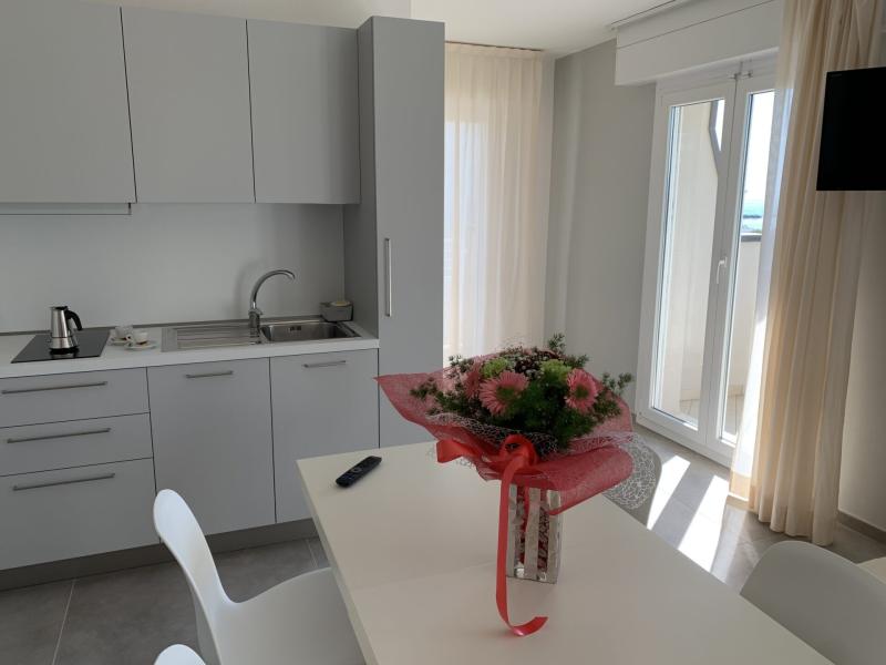 Cucina moderna con fiori rosa su tavolo bianco e luce naturale abbondante.
