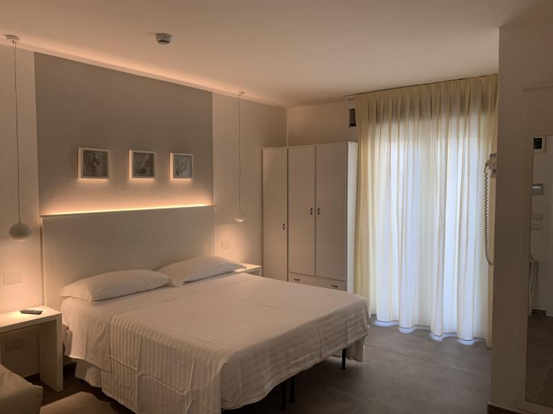 Camera moderna con letto matrimoniale, illuminazione soffusa e armadio bianco.
