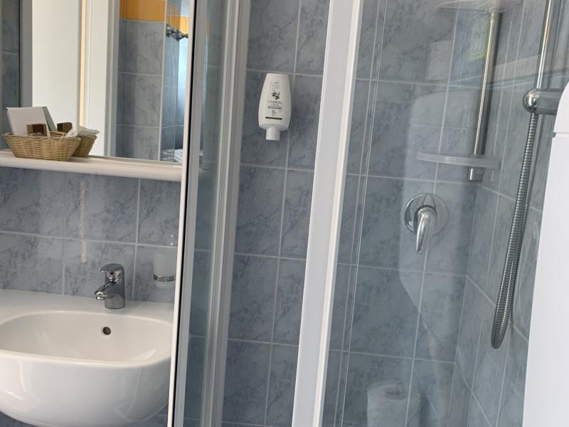 Bagno con doccia, lavabo, specchio e accessori su piastrelle blu e arancioni.