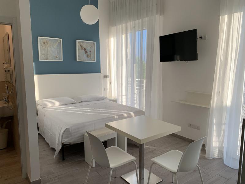 Camera moderna con letto matrimoniale, tavolo, TV a parete e decorazioni marine.