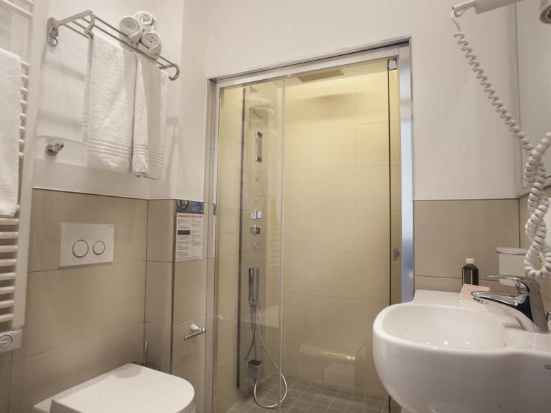Bagno moderno con doccia, lavabo, asciugamani e asciugacapelli a parete.